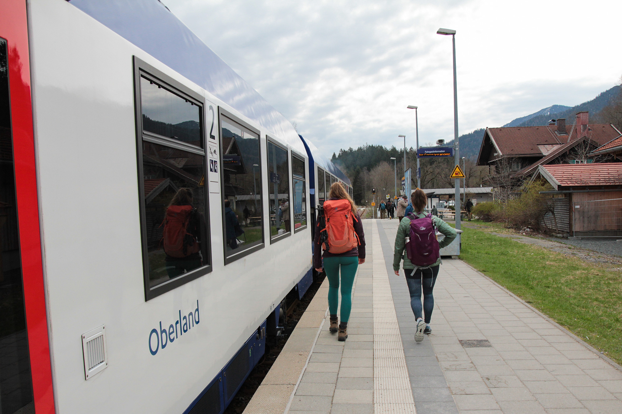 Bild Zwei junge Leute am Bahnsteig in einer Berglandschaft.