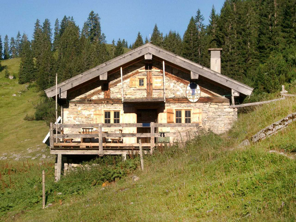 Bild Berghuette auf einer gruenen, sonnigen Almwiese.
