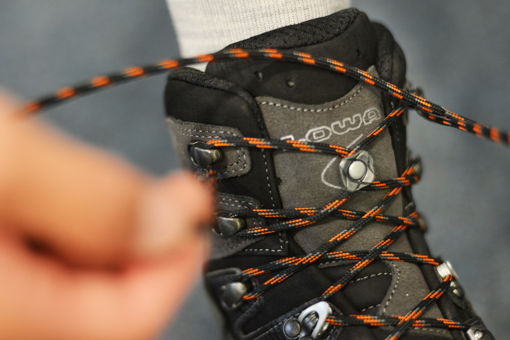 Bild Ein Bergschuh, bei dem man sieht, wie der obere Haken geschnuert wird