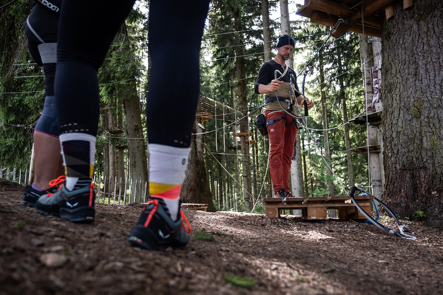 Bild Im Wald steht ein Mann und zeigt die Sicherungsmittel für den Hochseilgarten. 