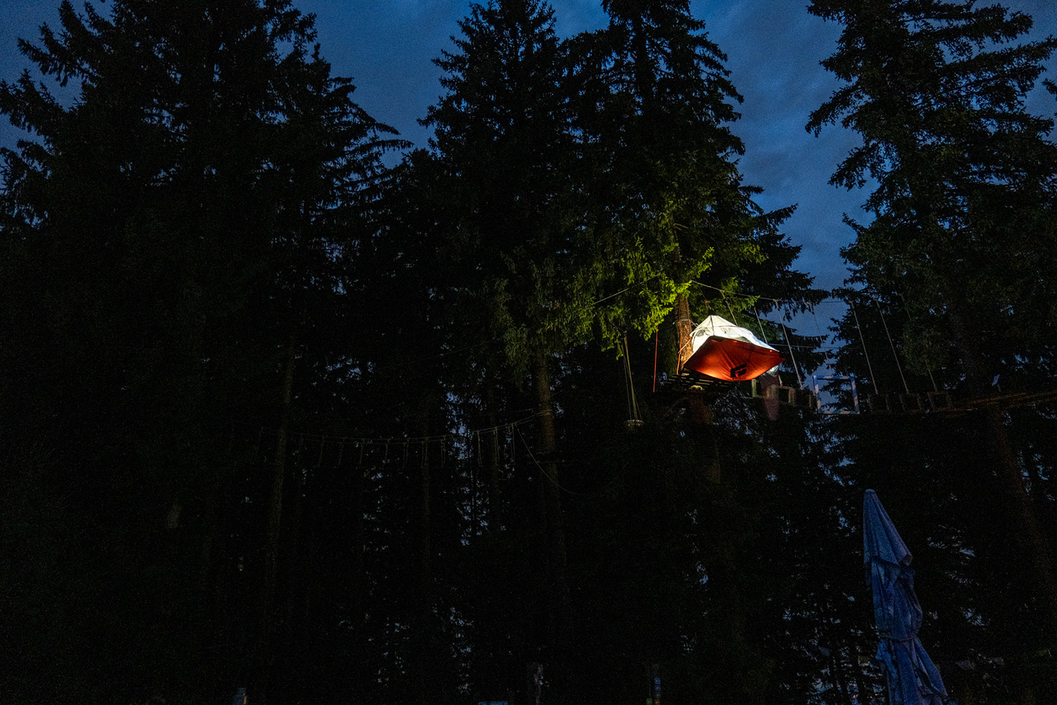Bild Aufnahme einer beleuchteten Portaledge, nachts im Wald.