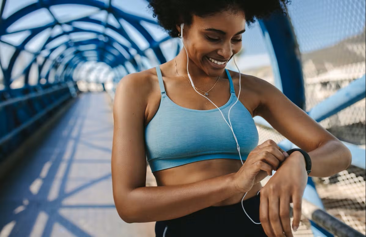 Bild Läuferin mit Ohrstöpsel drückt auf Ihre Uhr