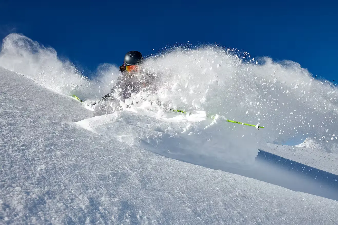 Bild Ein Skifahrer fährt durch eine steile Tiefschneeflanke ab. Nur der Kopf ist über dem staubenden Schnee zu erkennen.