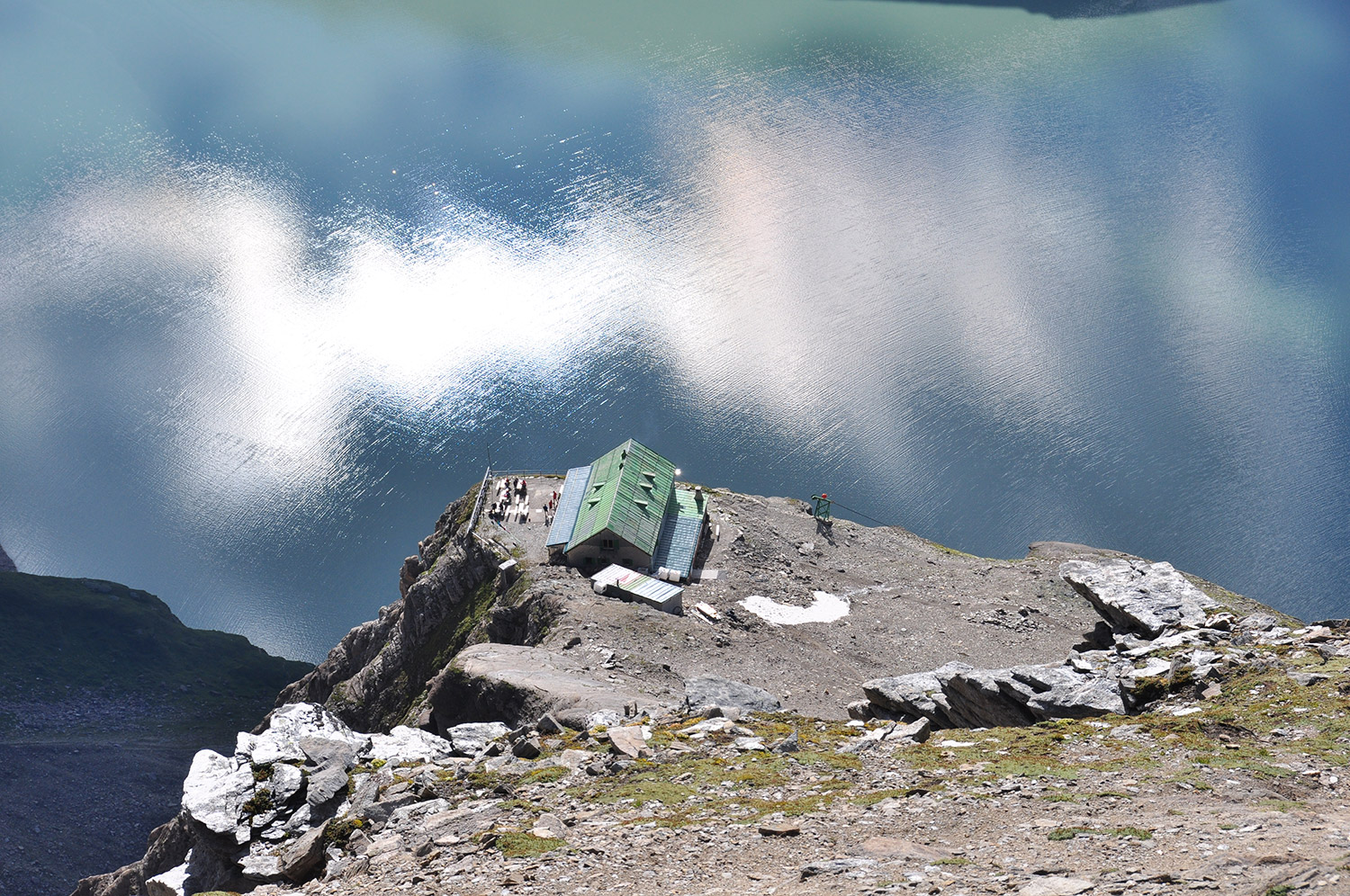 Bild Aufnahme vom Heinrich-Schwaiger-Haus von oben. Die Berghütte ist hoch über einem See zu sehen.