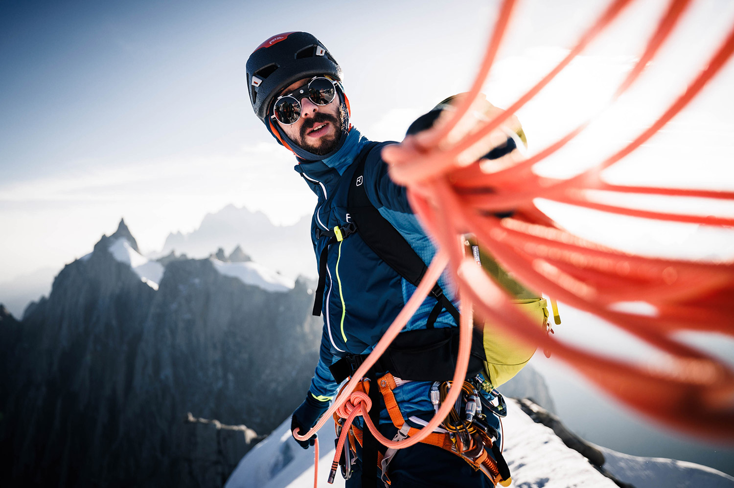 Bild Ein Bergsteiger hält ein oranges Kletterseil in der Hand und wickelt es auf.