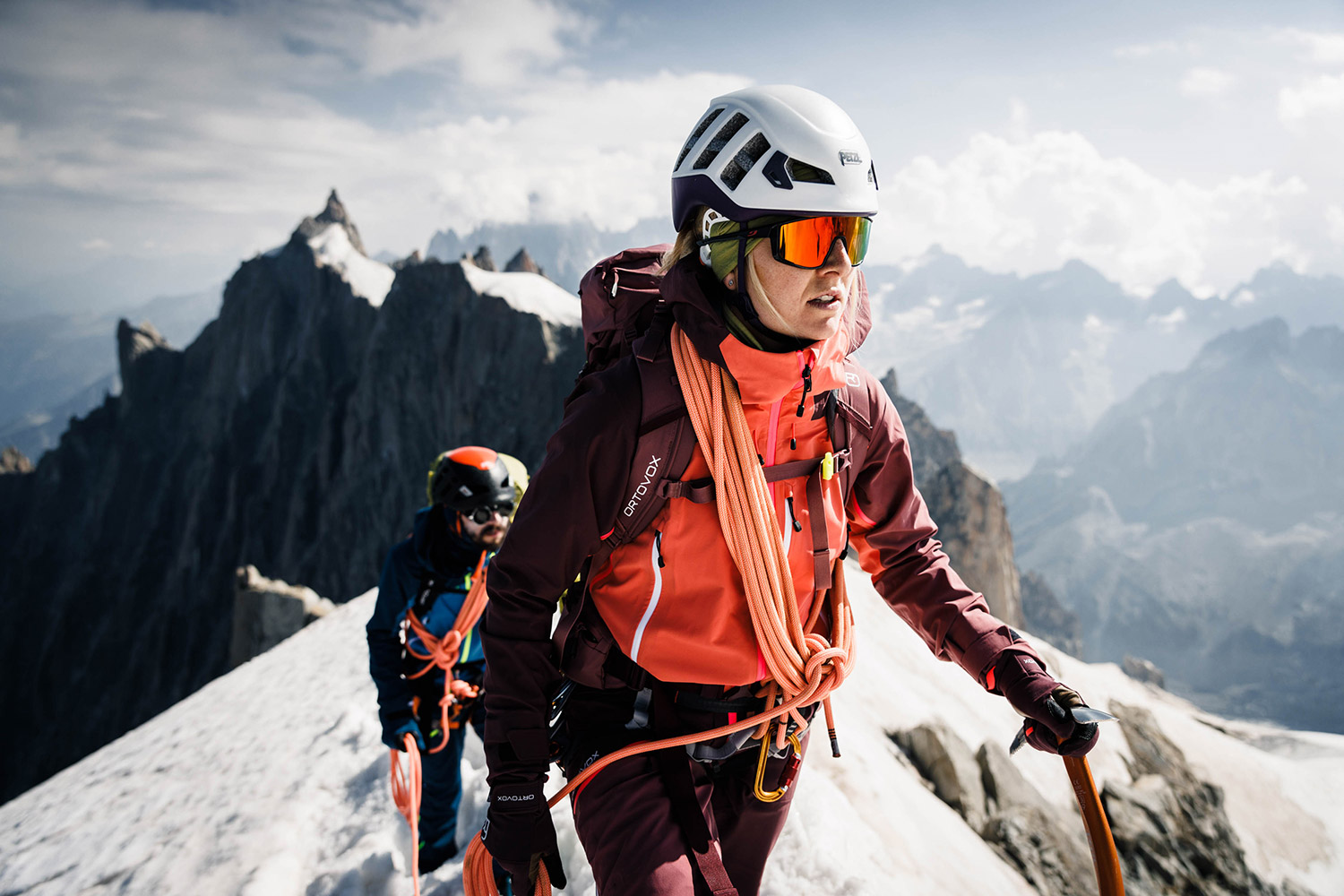 Bild Eine Bergsteigerin in Hochtouren-Bekleidung  auf einem schneebedeckten Bergkamm.