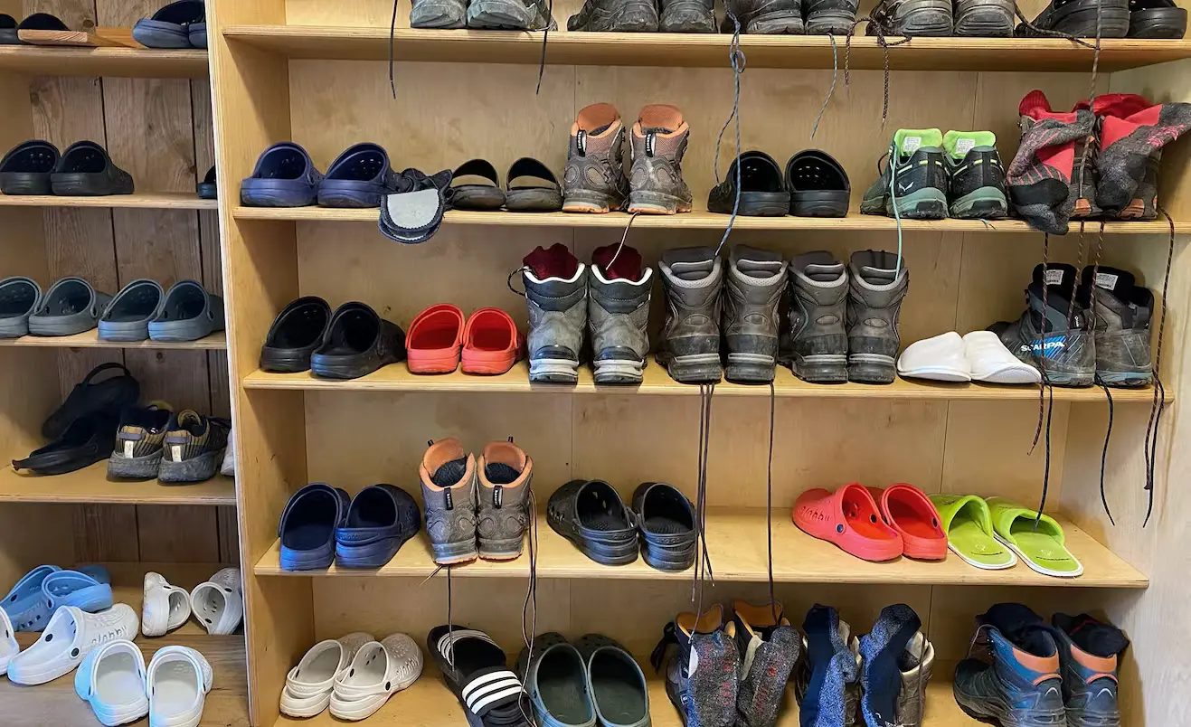 Bild Bild des Trockenraumes einer Berghütte. Man sieht ein volles Schuhregal.