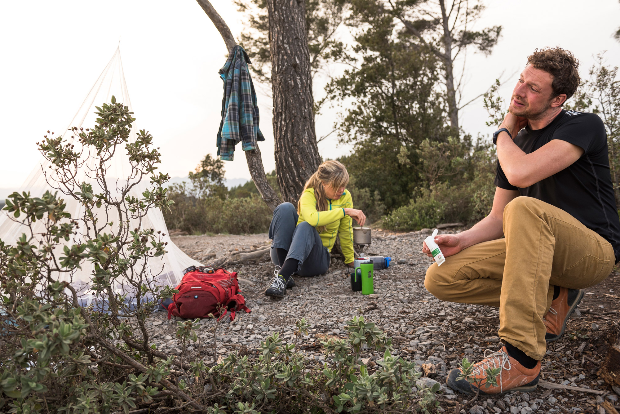Bild 2 Camper machen Pause in der Natur. Einer reibt seinen Nacken mit Insektenschutz ein.