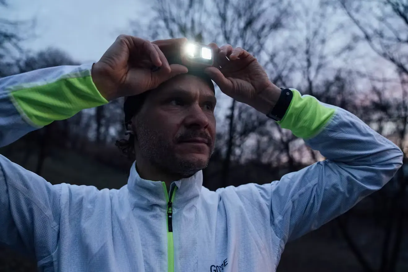 Bild Mann in Joggingbekleidung und Stirnlampe im Dämmerlicht.