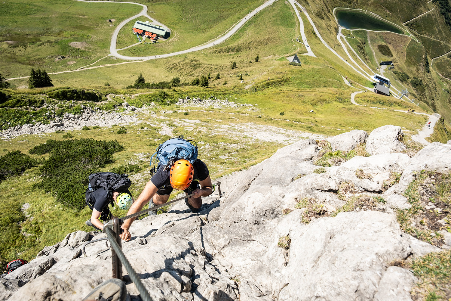 Bild Ein Mann mit orangenem Helm klettert in einem Klettersteig
