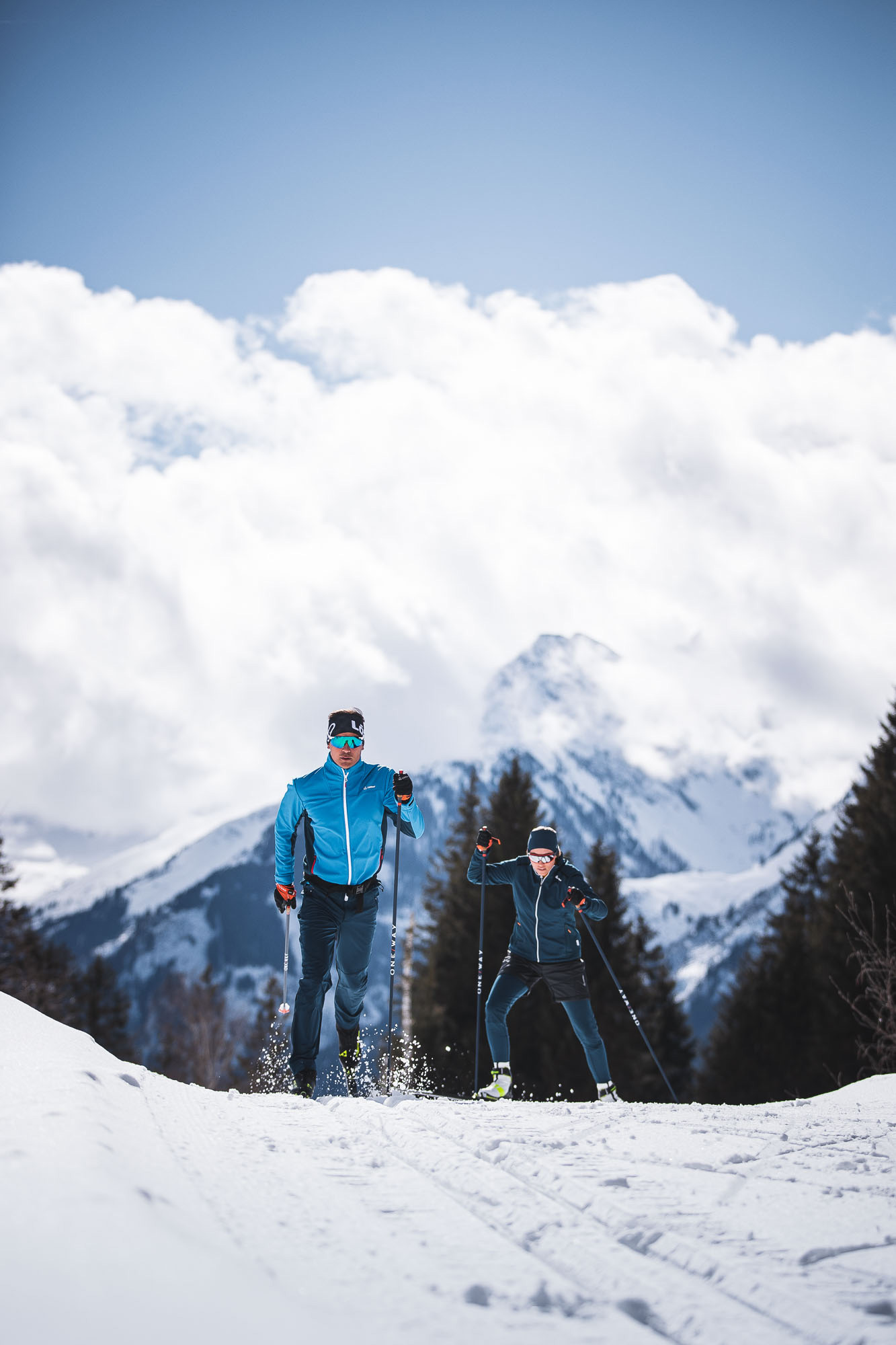 Ein Klassik-Langläufer und eine Skating-Langläuferin auf der Loipe
