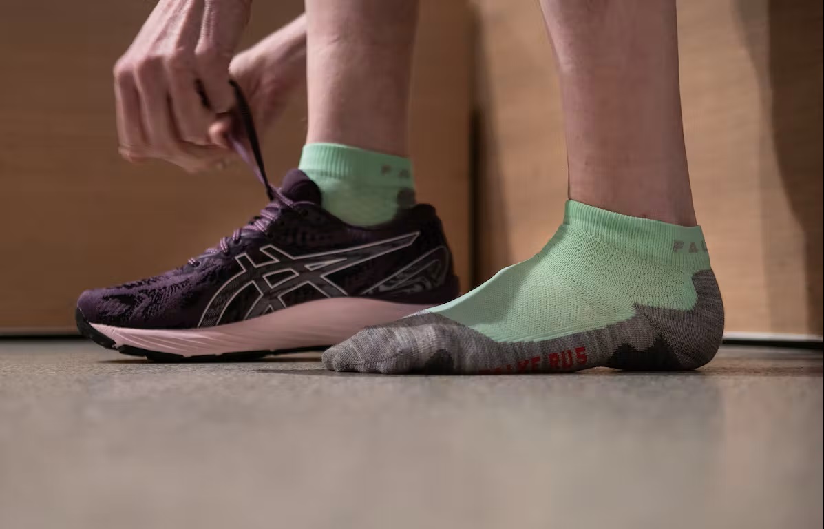 Bild Füße, die grüne Laufsocken von Falke tragen