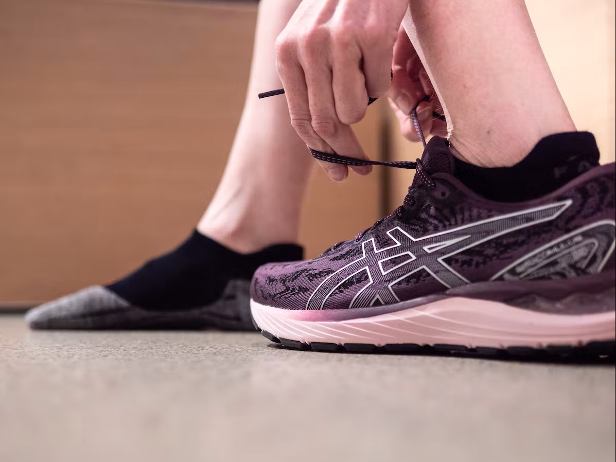Bild Füße, die einen Asics Laufschuh und schwarze Laufsocken tragen 