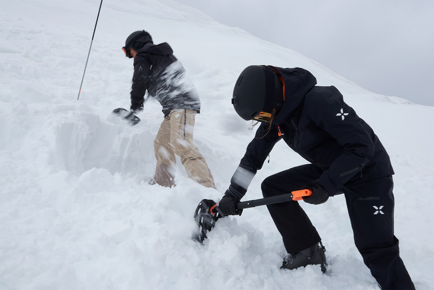 Zwei Personen graben mit Lawinenschaufeln im Schnee