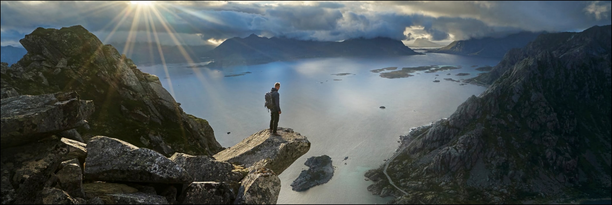 Person steht auf Felsvorsprung an Meer