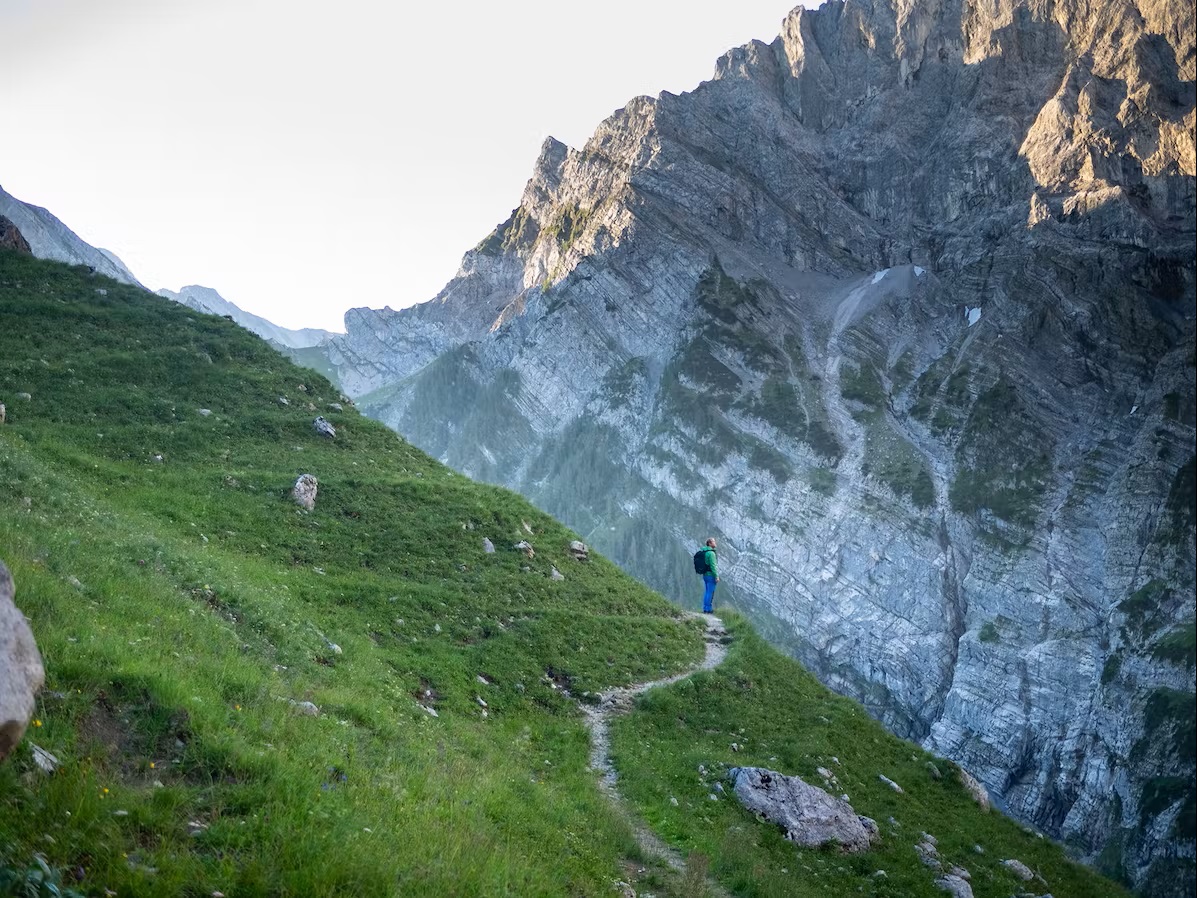 Bild Mann steht am Wanderweg und bewundert die Berge