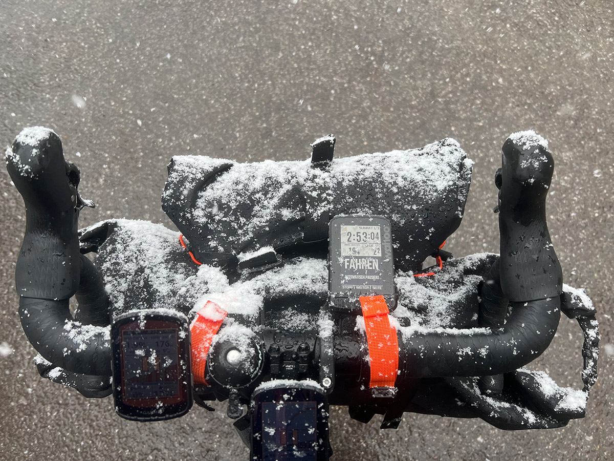 Bild Fahrradtaschen an einem Rennrad-Lenker. Alles ist verschneit und nass.
