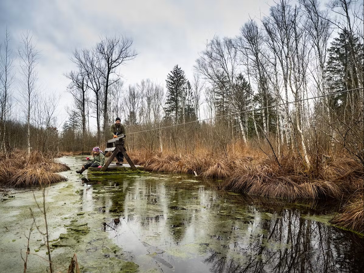 Bild Mann zieht Mädchen am Floss durch das Wasser im Bach 