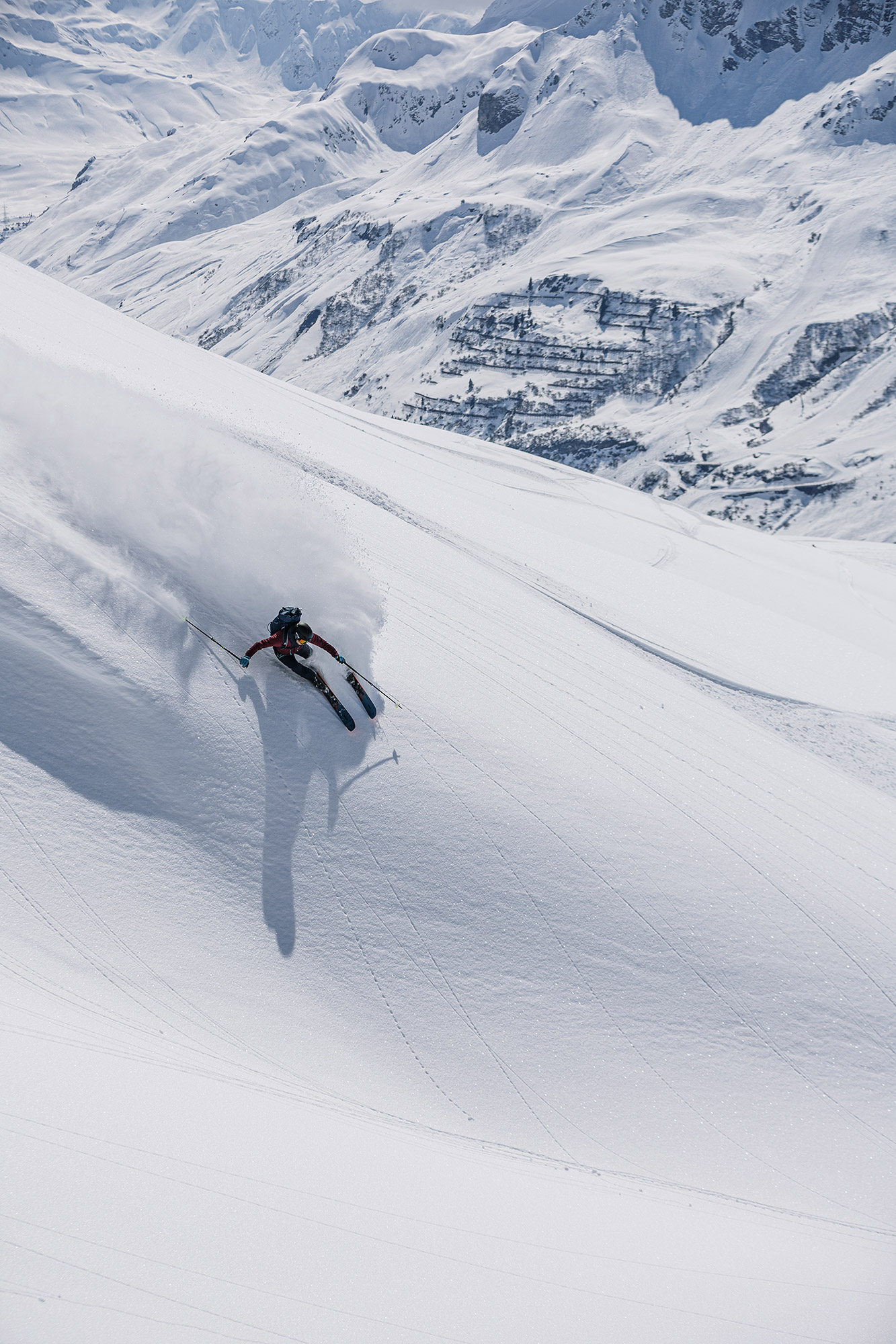 Bild Ein Skifahrer fährt einen steilen Hang herunter, der Pulverschnee staubt.