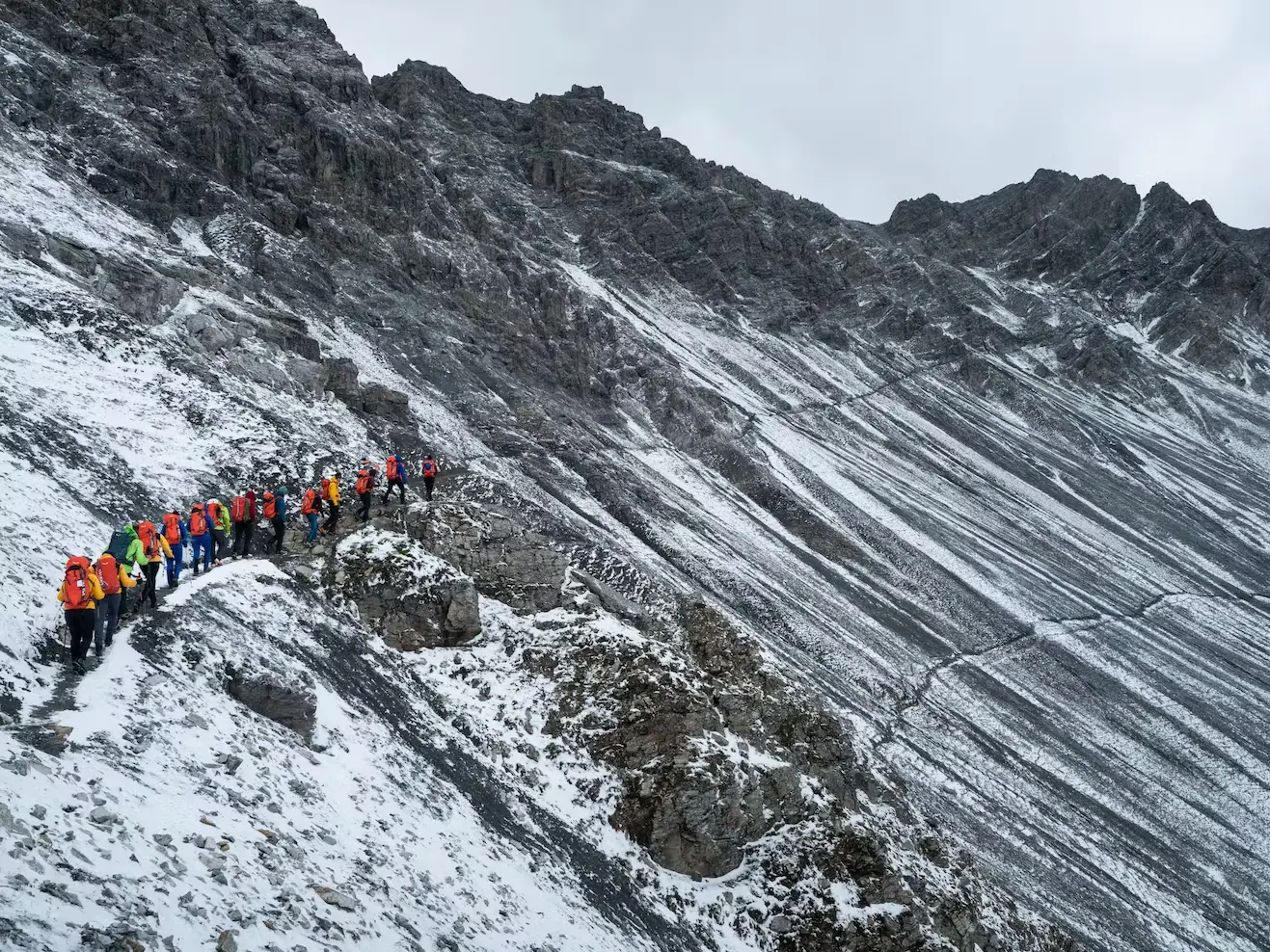 Bild Viele Bergsteiger in bunten Klamotten auf einer Bergflanke.