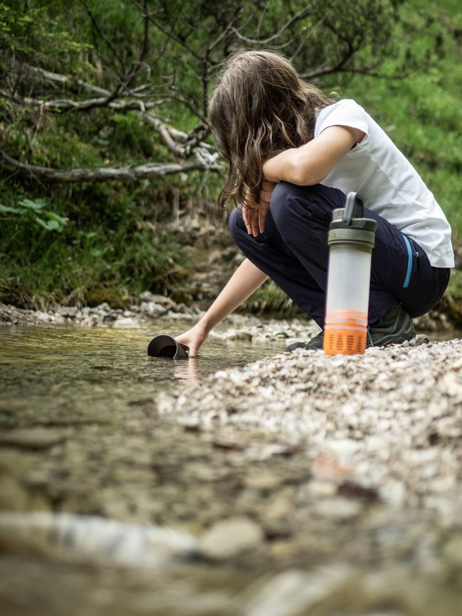 Bild Ein Mädchen schöpft Wasser aus einem Bach am Schildenstein