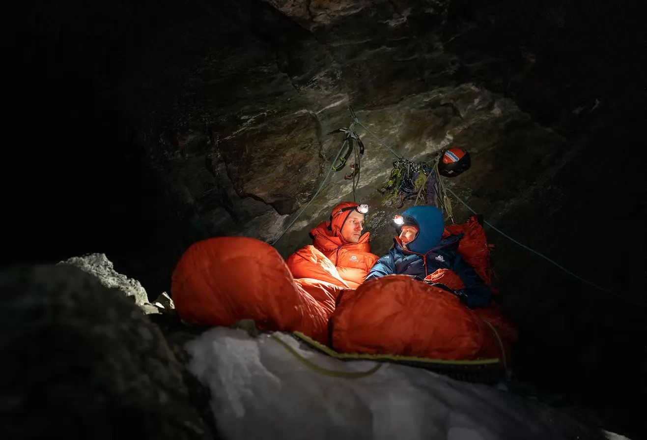Bild Zwei Bergsteiger in roten Schlafsäcken nachts im Biwak