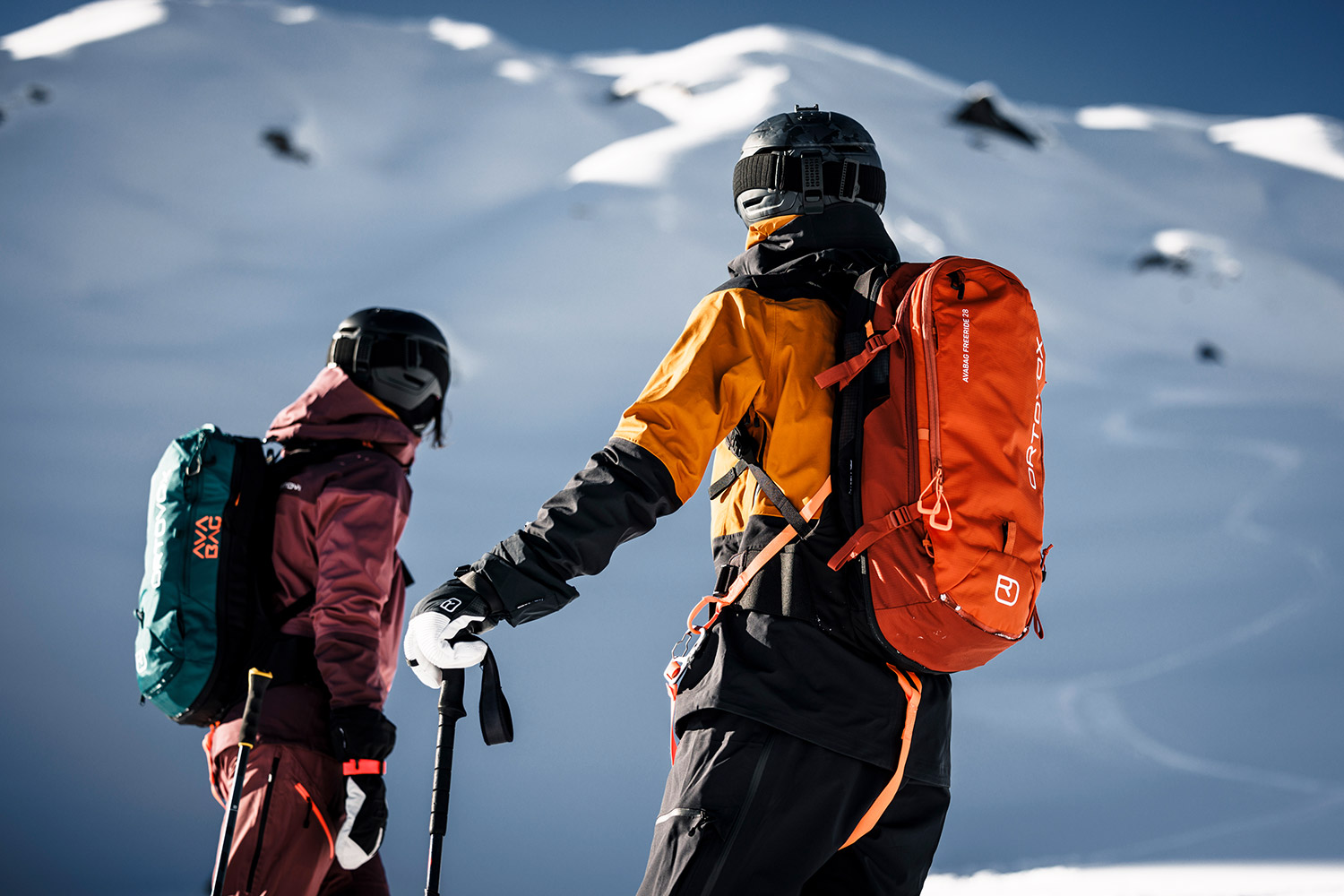 Bild 2 Skitourengeher mit Ortovox-Litric Rucksäcken an einem sonnigen, Hang im Schnee.