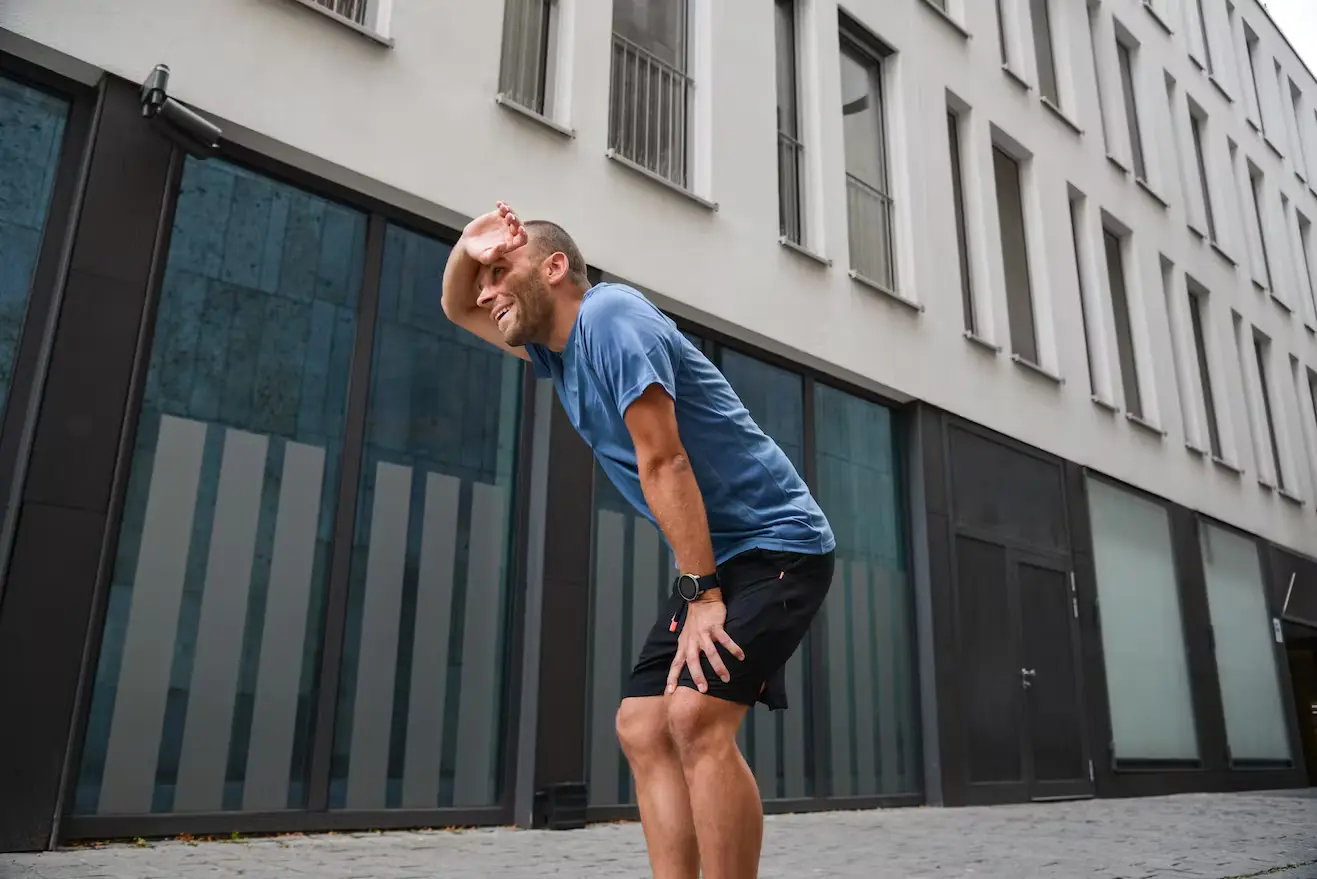 Bild Ein Läufer wischt sich erschöpft den Schweiß von der Stirn