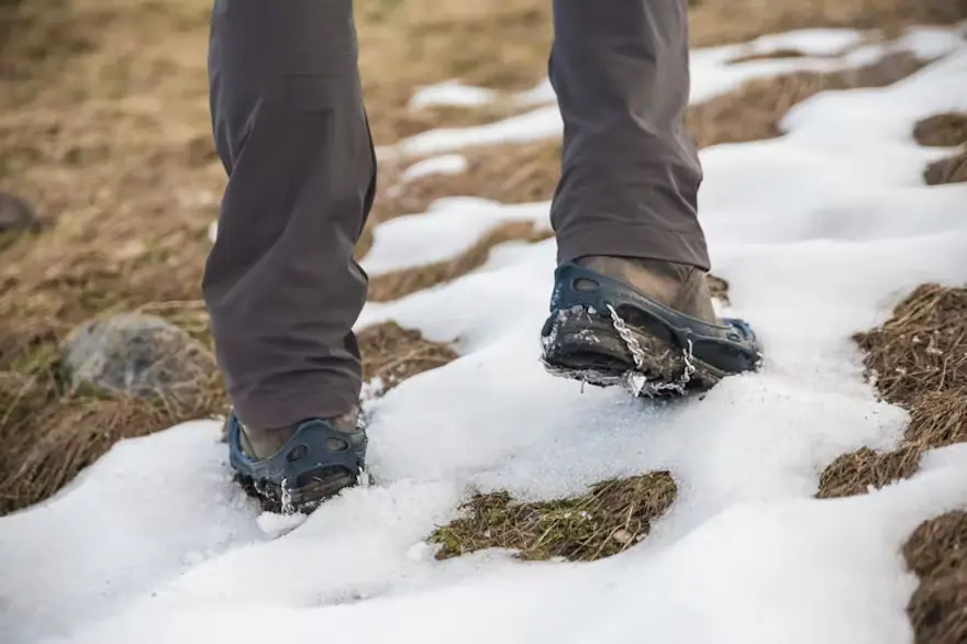 Schuh mit Spikes im Schnee beim Wandern