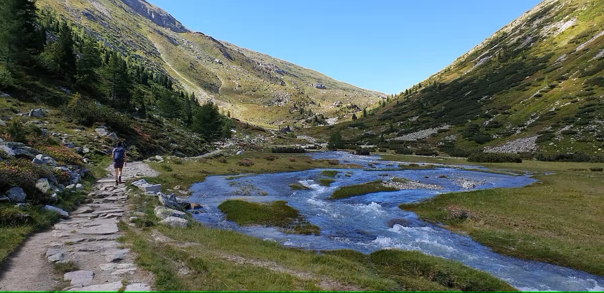 Bild Wanderer geht einen Weg am Bach entlang