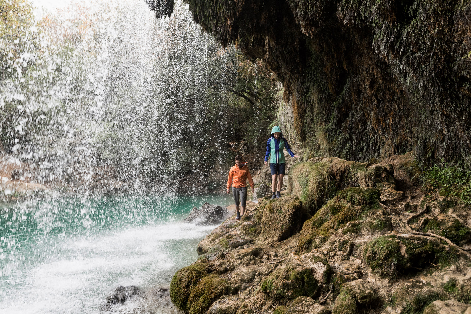 2 Personen mit Regenjacken vor einem Wasserfall