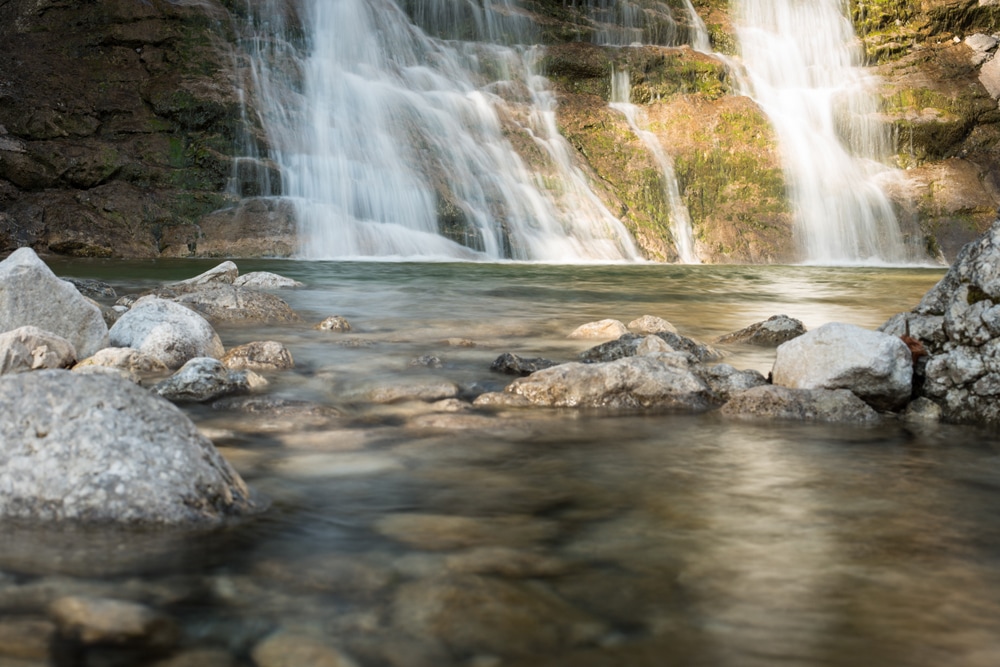 Wasserfall fließt in eine steinige Gumpe