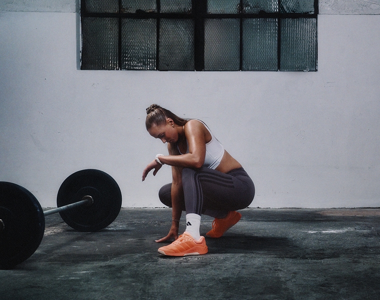 Frau mit adidas Trainingsschuhen beim Gewichtheben