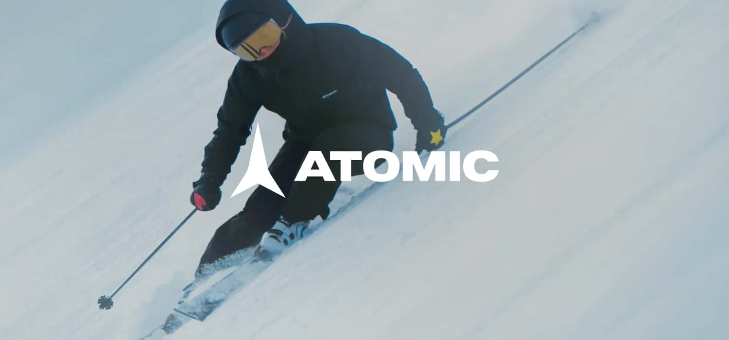 Skifahrer auf einer Piste und Atomic Logo