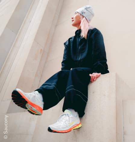 Frau mit Sneakern sitzt auf einem Podest