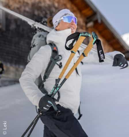 Frau trägt Skitourenstöcke in der Hand