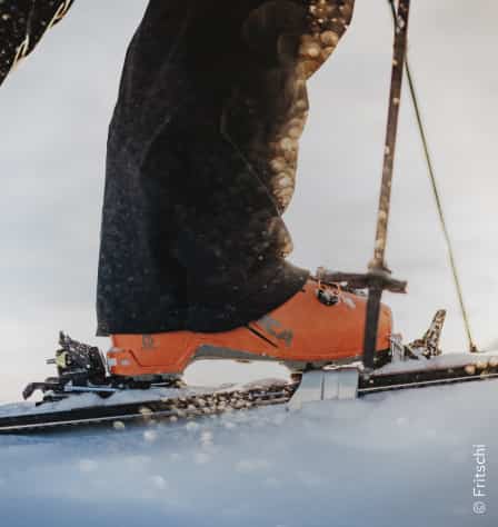 Skitourenbindung mit orangefarbenem Skischuh darauf
