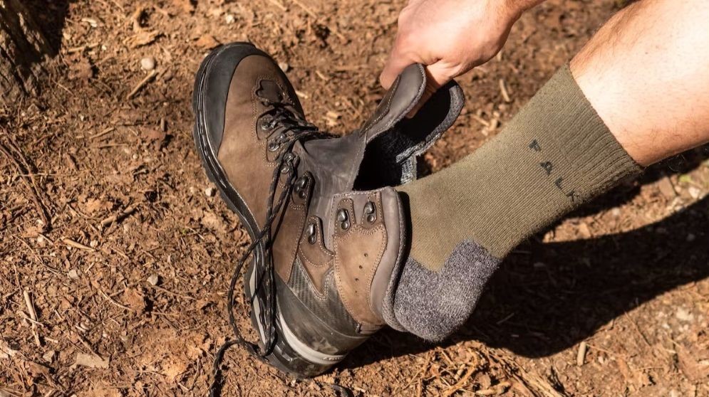 Wanderer mit Falke Wandersocken sieht seinen Wanderschuh an
